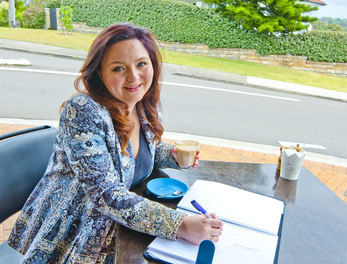 Lauren Jobson journaling with a coffee at an outdoor cafe